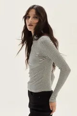 Polera de manga larga con cuello alto, confeccionada en tejido de punto acanalado con diseño de rayas horizontales en color marrón y turquesa. Presenta un bordado pequeño en el pecho y un calce ajustado al cuerpo.