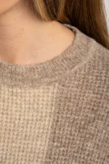 Sweater de tejido de punto grueso, con diseño de rayas verticales anchas en tonos marrón oscuro y negro. Presenta cuello redondo y mangas largas.