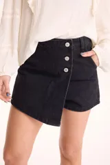 Short pollera de jean negro con spandex, diseño cruzado en el frente y cierre de botones metálicos en la parte superior.