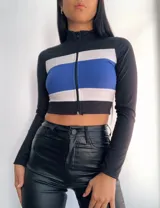 Top manga larga con cierre frontal y diseño tricolor con franjas horizontales en negro, blanco y rojo, fucsia, violeta o azul.