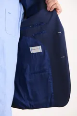 Saco azul oscuro de corte entallado, con solapa de muesca, cierre de dos botones, bolsillo de ribete en el pecho y bolsillos de parche en los laterales.