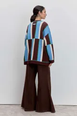 Cardigan de punto con diseño de bloques de color en azul, rojo y crema. Presenta cuello en V, cierre frontal con botones, mangas largas y dos bolsillos delanteros con bordado de cerezas.