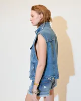 Chaleco de denim celeste con cuello alto, mega sisa y corte boxy. Tiene bolsillos plaqué en el pecho, bolsillos ojal en los laterales y presillas en el ruedo trasero para ajustar.