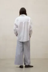 Camisa Daria holgada de lino blanco, con cuello camisero, cierre frontal de botones y mangas largas.