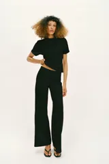 Pantalón largo negro de tiro alto, confeccionado en tejido elástico, con cintura elástica y diseño de pierna ancha tipo palazzo con bajo evasé.