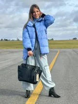 Bolso negro tipo tote de cuero con correa de hombro, hebilla decorativa y etiqueta colgante con la inscripción "NADIA".