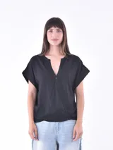 Blusa negra de corte holgado con escote en V profundo y diseño cruzado frontal. Presenta mangas cortas con dobladillo y una caída fluida.