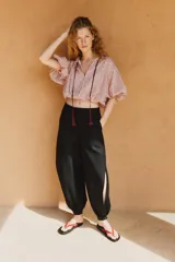 Pantalón bombacho de tiro medio confeccionado en lino, color negro, con pernera abullonada y bajo acabado en puño con botón.