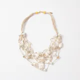 Collar de múltiples hilos de tejido color beige, adornado con perlas barrocas y cuentas de cristal transparente. Presenta cierre de mosquetón con terminales metálicos dorados.
