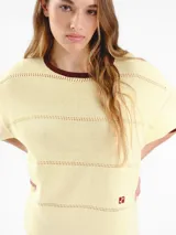 Vestido midi de punto de manga corta con detalles calados y diseño de rayas horizontales tricolor en la parte inferior. Presenta cuello redondo y logo bordado en el pecho.