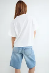 Bermuda de denim color blanco off-white, de tiro alto y corte recto y holgado, con bolsillos laterales y traseros.
