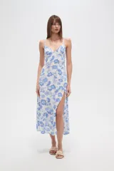 Vestido largo de viscosa, estampado en tonos blanco y azul con diseño floral tipo cachemir. Presenta escote en V, tirantes finos, talle ajustado con cordón y abertura lateral en la falda.