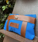 Sobre tipo cartuchera de lona con estampado de camuflaje y terminaciones en cuero marrón.