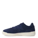 Championes urbanos New Balance en color azul marino, confeccionados en gamuza con detalles de costuras y logo lateral característico. Presentan cierre mediante cordones al tono y una suela de goma en color crema con diseño texturizado.