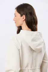 Campera liviana con capucha, de corte clásico, color beige, con bolsillos laterales con solapa y cierre frontal.