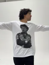 Remera de manga larga color blanco con estampado fotográfico frontal de Ayrton Senna con su traje de piloto de Fórmula 1. Presenta un corte holgado y cuello redondo.