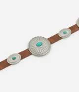 Cinturón de cuero sintético color marrón con hebilla ovalada y apliques metálicos circulares decorados con piedras turquesas.