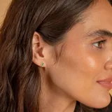 Aros tipo caravana de oro 18k con esmeralda central en corte ovalado rodeada por un halo de brillantes.