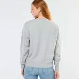 Buzo de cuello redondo en color gris melange, con mangas largas y corte holgado. Presenta un estampado frontal con la inscripción 'NEW YORK' y un logo circular estilo universitario con el texto 'MEMBER CLUB' en color bordó.