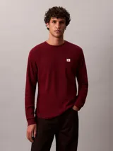Remera de manga larga Calvin Klein en tejido térmico de punto con textura tipo nido de abeja, color bordó, de corte regular con cuello redondo y puños acanalados. Cuenta con un pequeño parche con el logo de la marca en el pecho.