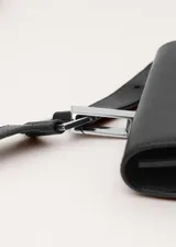 Cinturón de cuero vacuno color negro con hebilla metálica cuadrada y monedero desmontable colgante con solapa y cierre de botón a presión.