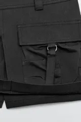 Falda pantalón satinada de tiro medio y color negro, con bolsillos cargo de plastrón con solapa, pliegues decorativos en el delantero y cierre lateral con cremallera oculta.