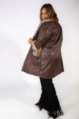 Tapado de cuero sintético color marrón con interior y detalles de piel sintética con estampado animal print de leopardo en cuello, puños y bolsillos frontales. Cuenta con cierre frontal de dos botones.