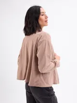 Campera de pana color beige, con cuello camisero, cierre frontal de botones oscuros, mangas largas con puños abotonados y dos bolsillos frontales con solapa.