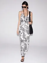 Mono largo de viscosa color blanco con estampado de flores y hojas en negro. Tiene breteles finos, corte amplio y bolsillos laterales.