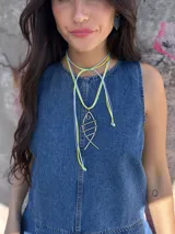 Collar con tres tientos sintéticos en colores amarillo, celeste y lila, con medallón de alambre plateado en forma de pez. Tiene un nudo corredizo para poder usar de varias formas.