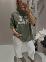 Remera gris con efecto acid wash y diseño oversize. Presenta un estampado frontal con la inscripción "KILLING IN THE NAME OF" y la frase "NOW YOU DO WHAT THEY TOLD YA".