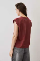 Remera sin mangas bordó con hombreras marcadas y cuello redondo.