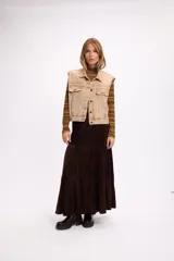 Chaleco de denim con lavado desgastado, corte relajado, cuello camisero, cierre frontal con botones metálicos y bolsillos con solapa en el pecho.