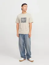 Remera color arena de manga corta y cuello redondo, con estampado cuadrado en el frente con diseño de camuflaje y logo de la marca.