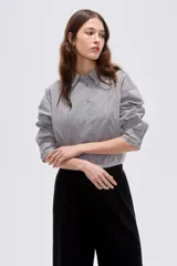 Camisa de algodón a rayas grises y blancas, de corte holgado, con cuello camisero, manga larga y cierre frontal de botones.