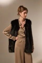 Chaleco sin mangas de piel sintética en color negro, con diseño abierto y corte recto.