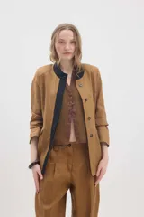 Chaqueta de lino marrón con cuello mao en contraste negro, cierre frontal con botones y hombreras.