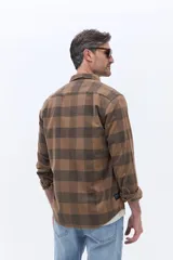 Camisa de manga larga confeccionada en viyela de algodón con diseño a cuadros en tonos verde oscuro. Presenta cuello clásico, cierre frontal con botones y bolsillo aplicado en el pecho.