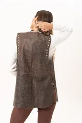 Chaleco de cuero marrón con silueta relajada, caracterizado por detalles de ojalillos metálicos a lo largo de los bordes frontales.