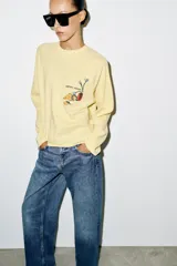 Camiseta de manga larga ranglán y cuello redondo, color amarillo, con estampado frontal a contraste.