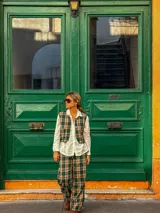 Chaleco de corte sastrero con estampado de cuadros en tonos verde, beige y negro, con cierre frontal de botones.