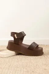 Sandalias de plataforma color negro, con diseño de dos tiras anchas en el empeine y cierre con velcro en el tobillo. Presentan una suela de plataforma alta y liviana.