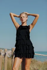 Vestido mini negro de cuello halter y espalda descubierta, con diseño de múltiples volantes en cascada.
