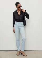 Jeans mom-fit de tiro alto en color celeste claro, con diseño de cinco bolsillos, trabillas para cinturón y cierre frontal con cremallera y botón.