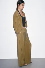 Pantalón tipo palazzo de corte recto y tejido fluido, color naranja. Presenta cintura elástica con cordón ajustable y bolsillos laterales.