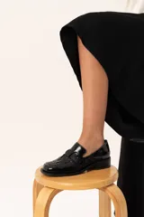 Mocasín de cuero charol negro con diseño enrejillado en la capellada, horma cuadrada y taco bajo.