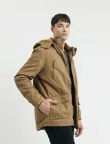 Campera de abrigo estilo parka, color verde oscuro, con capucha desmontable, cierre frontal con botones y cremallera, múltiples bolsillos frontales y en la manga.