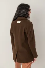 Blazer de paño de lana color marrón chocolate, con cuello mao y un solo botón frontal. Presenta un bolsillo superior de ojal y dos bolsillos de parche inferiores.