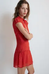 Vestido corto rojo con estampado de lunares blancos, cuello redondo con escote en pico pronunciado, manga muy corta y cierre frontal con botones.