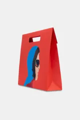 Bolsa tipo shopper de algodón en color rojo, con estampado frontal de collage fotográfico inspirado en películas de Almodóvar. Cuenta con dos asas largas para llevar al hombro.